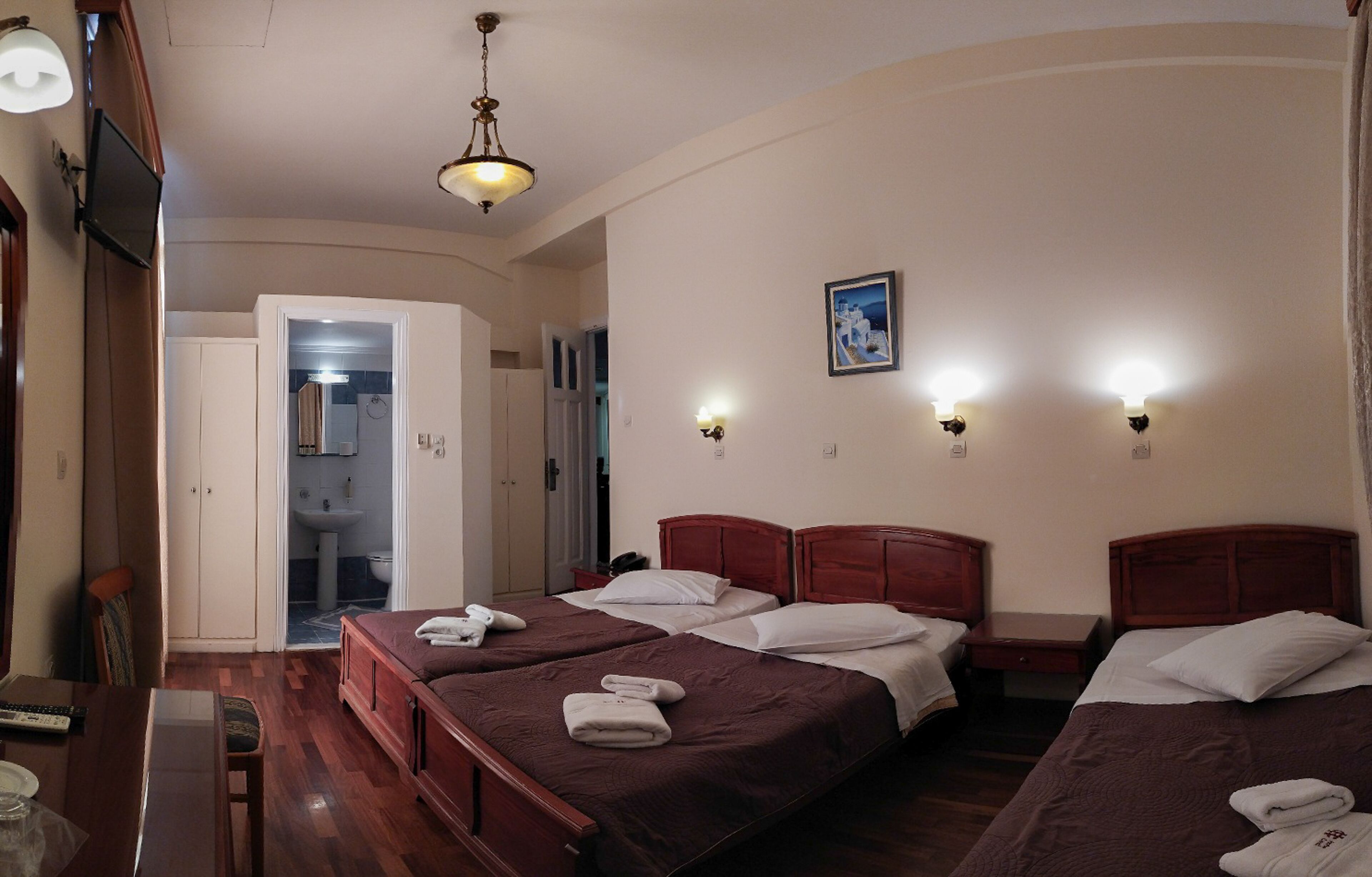 A hotel room with two beds, a desk, a chair, and a bathroom visible through an open door.