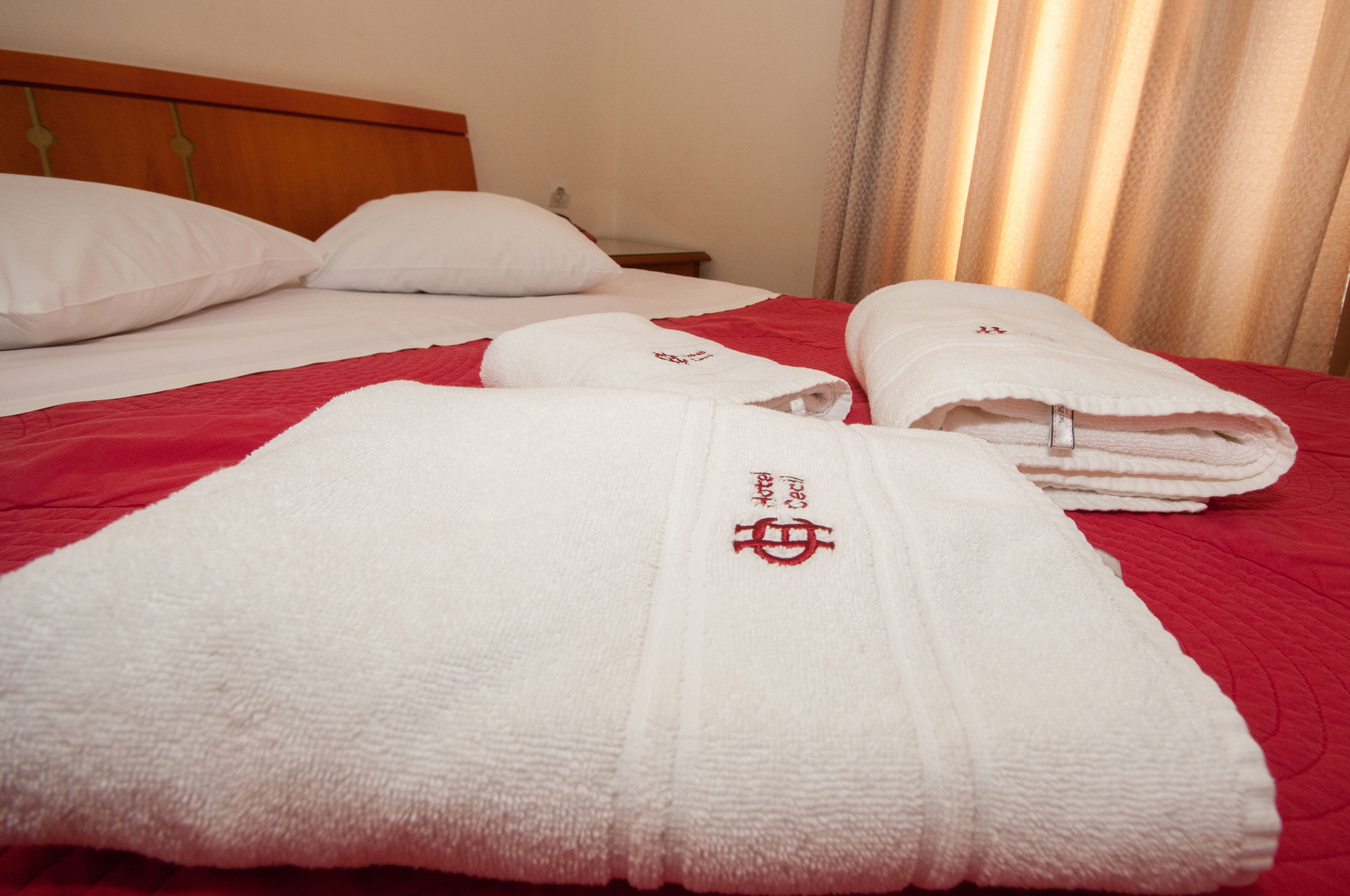 Una cama bien hecha con almohadas blancas y una colcha roja.