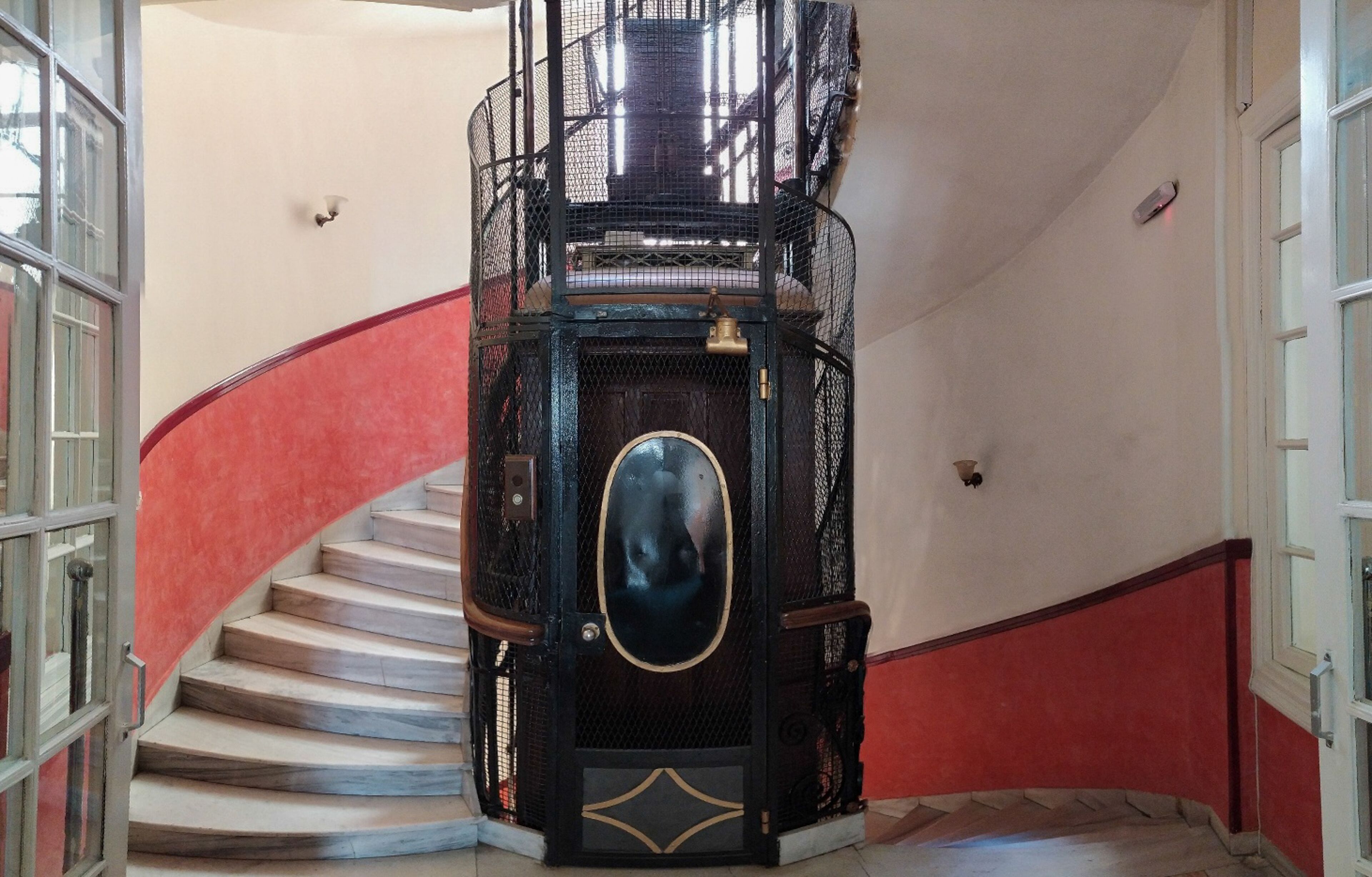 A spiral staircase with a black metal railing and a decorative oval mirror at the center.