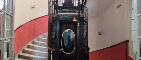 A spiral staircase with a black metal railing and a decorative oval mirror at the center.