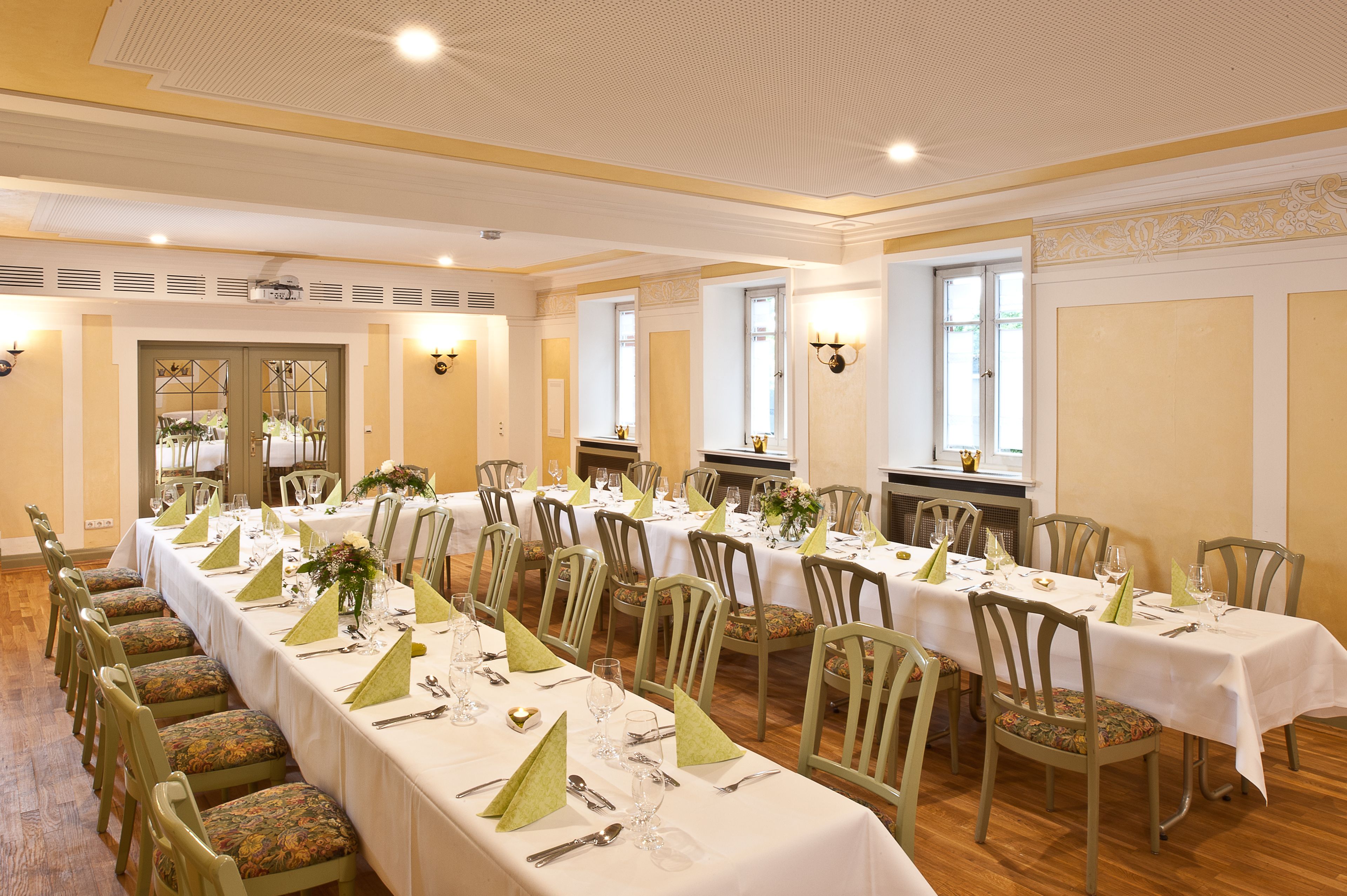 Ein Banketthaus mit langen Tischen, gedeckt für ein Essen, ausgestattet mit Stühlen und Tischdecken.