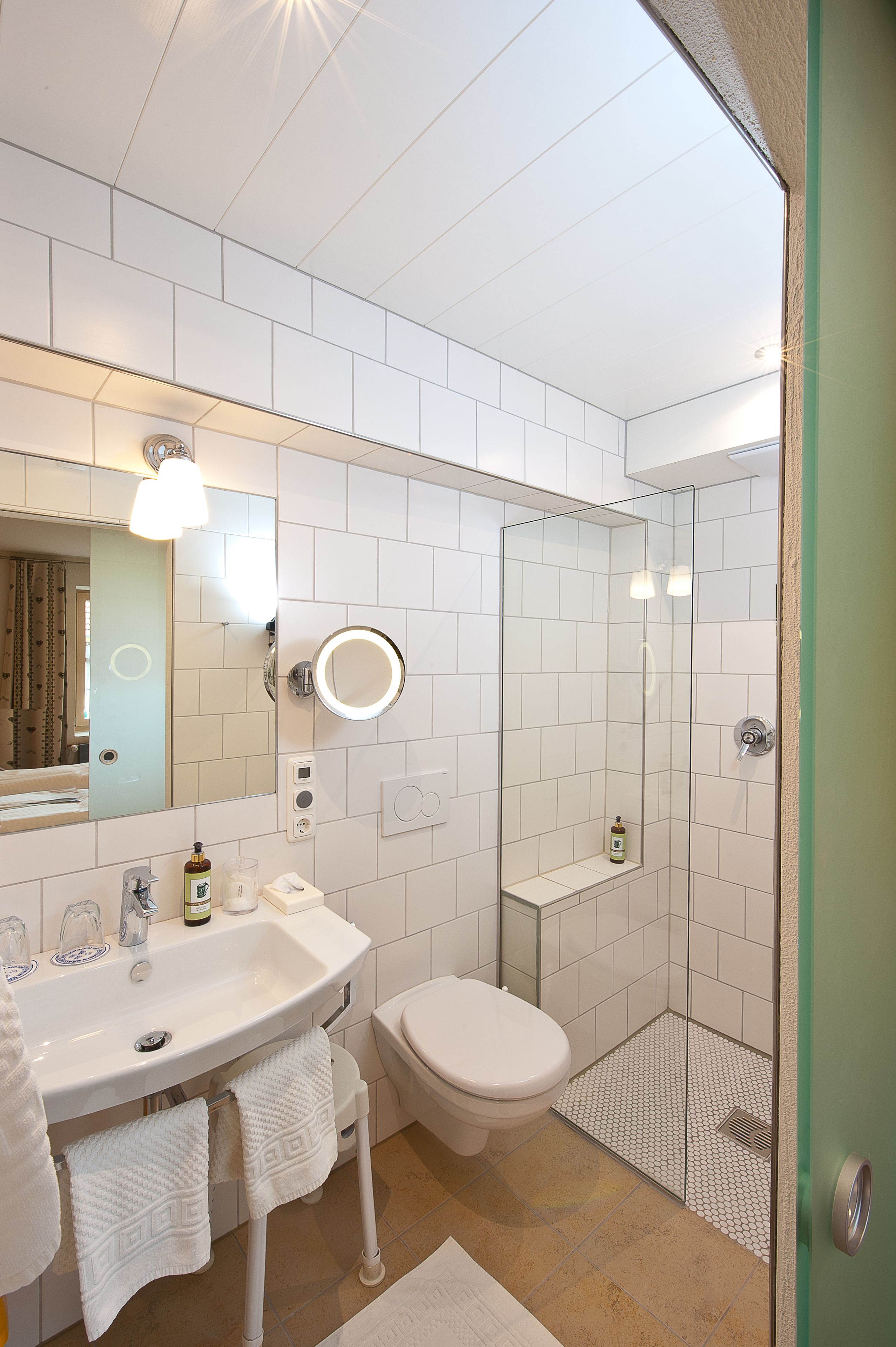 A modern bathroom with a white sink, mirror, and toilet.