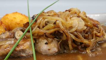 A dish with chicken, onions, and a side of potatoes.
