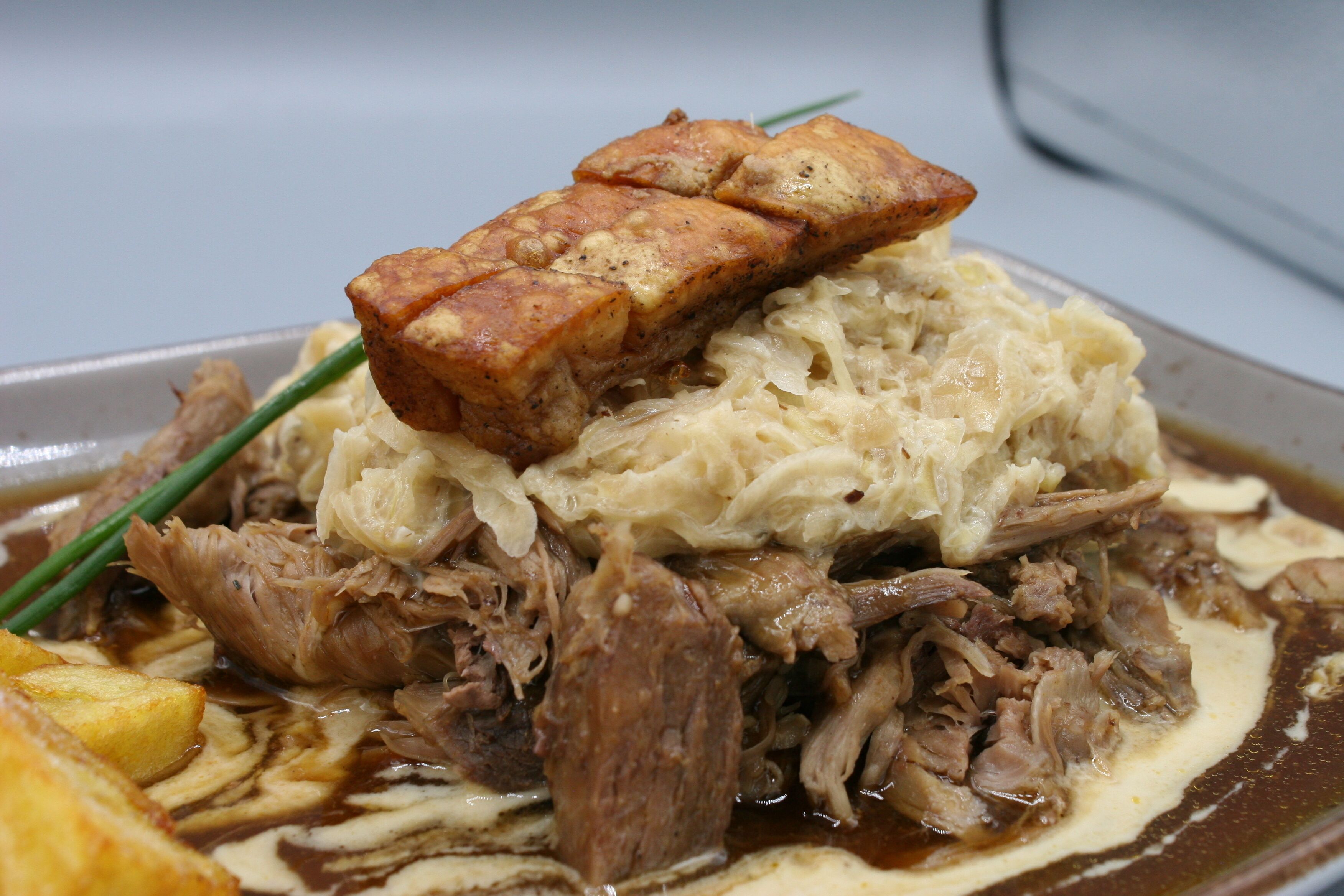 A dish with shredded meat, sauerkraut, and a piece of fried food on a plate.