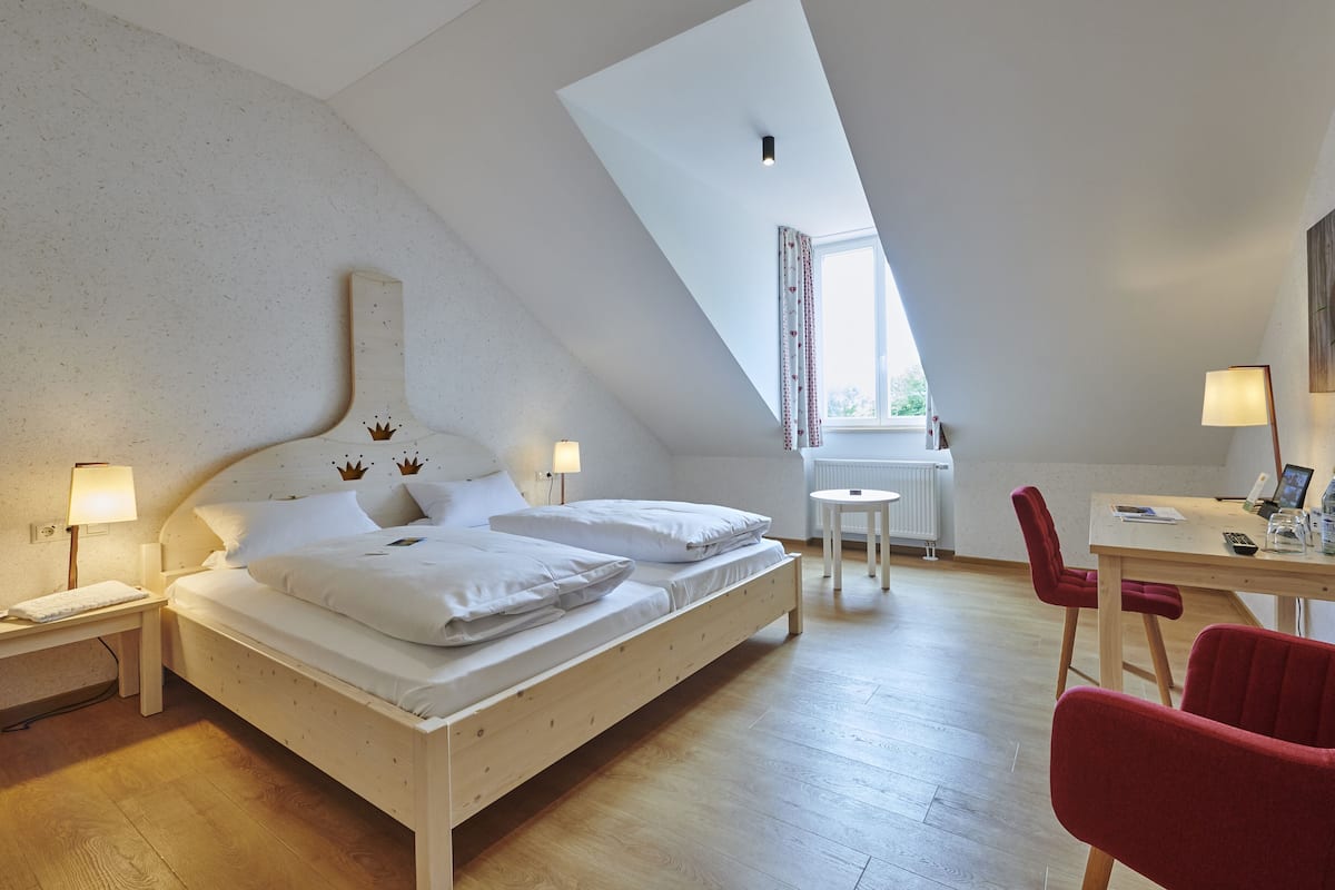 A bedroom with a bed, bedside tables, a desk, and a chair.