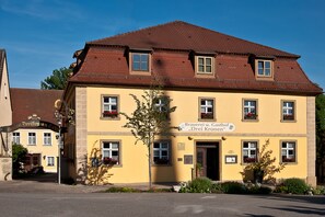 A yellow building with a brown roof, multiple windows, and a sign indicating it is a restaurant. - Hotel & Brauereigasthof Drei Kronen (Memmelsdorf)