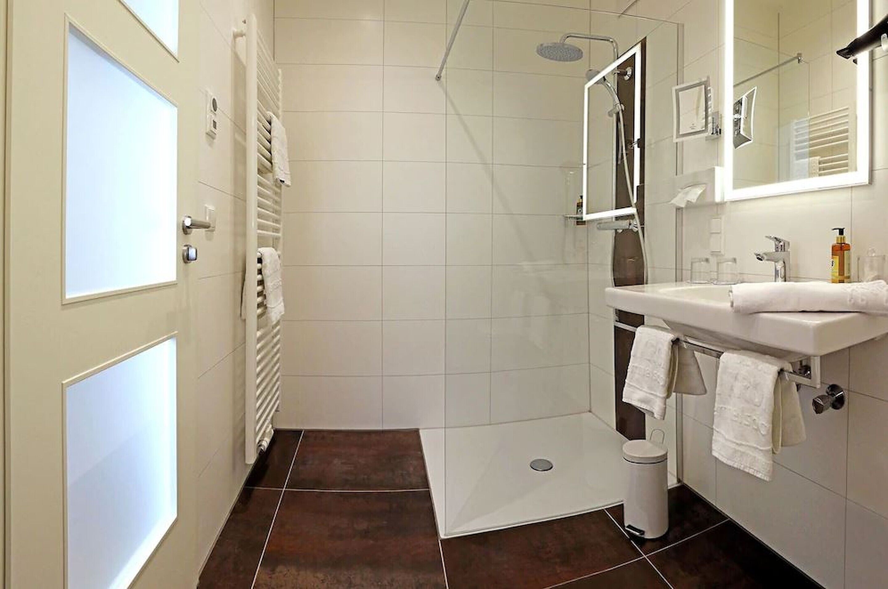 A modern bathroom with a shower, sink, and mirror.