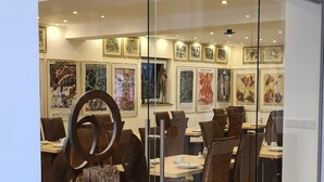 A modern interior with a glass partition, wooden chairs, and artwork on the walls. - Hotel Garni Am Ellinger Tor (Weissenburg in Bayern)