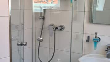 Un baño moderno con ducha envuelta en vidrio, un lavamanos blanco y un espejo.