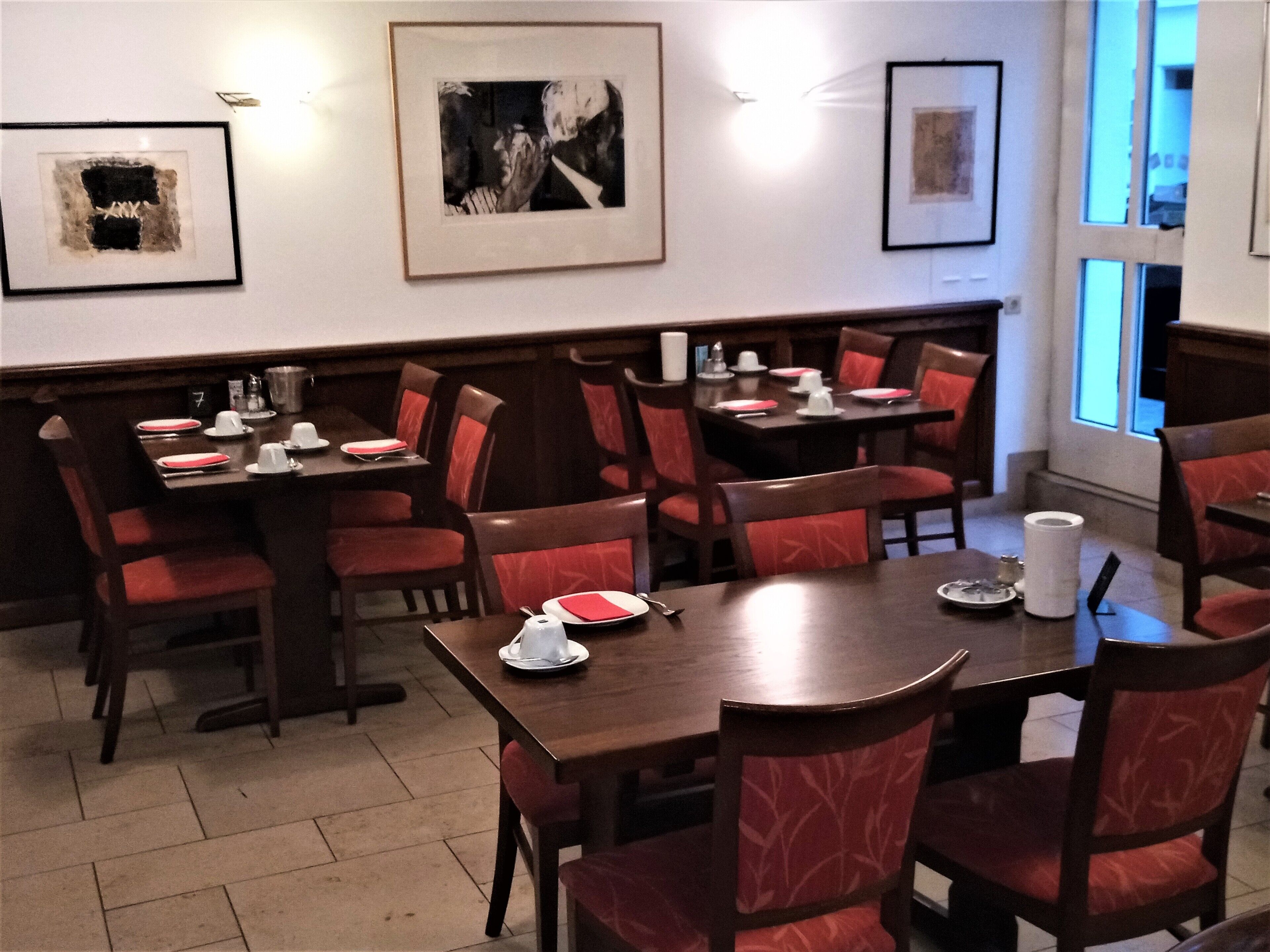 Un restaurante con varias mesas y cabinas, obras de arte en las paredes y vistas al exterior a través de las ventanas.