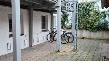 A covered outdoor area with a white wall, a brick floor, and a bicycle parked against the wall.