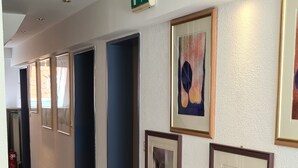 A hallway with framed artwork on the walls, a fire extinguisher, and a door at the end. - Hotel Garni Am Ellinger Tor (Weissenburg in Bayern)