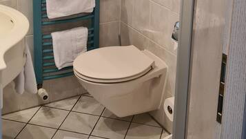 Une salle de bain comprenant des toilettes, un bidet et un espace douche.