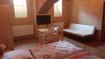 Una habitación acogedora con una mesa de madera, sillas, un sofá y un televisor.