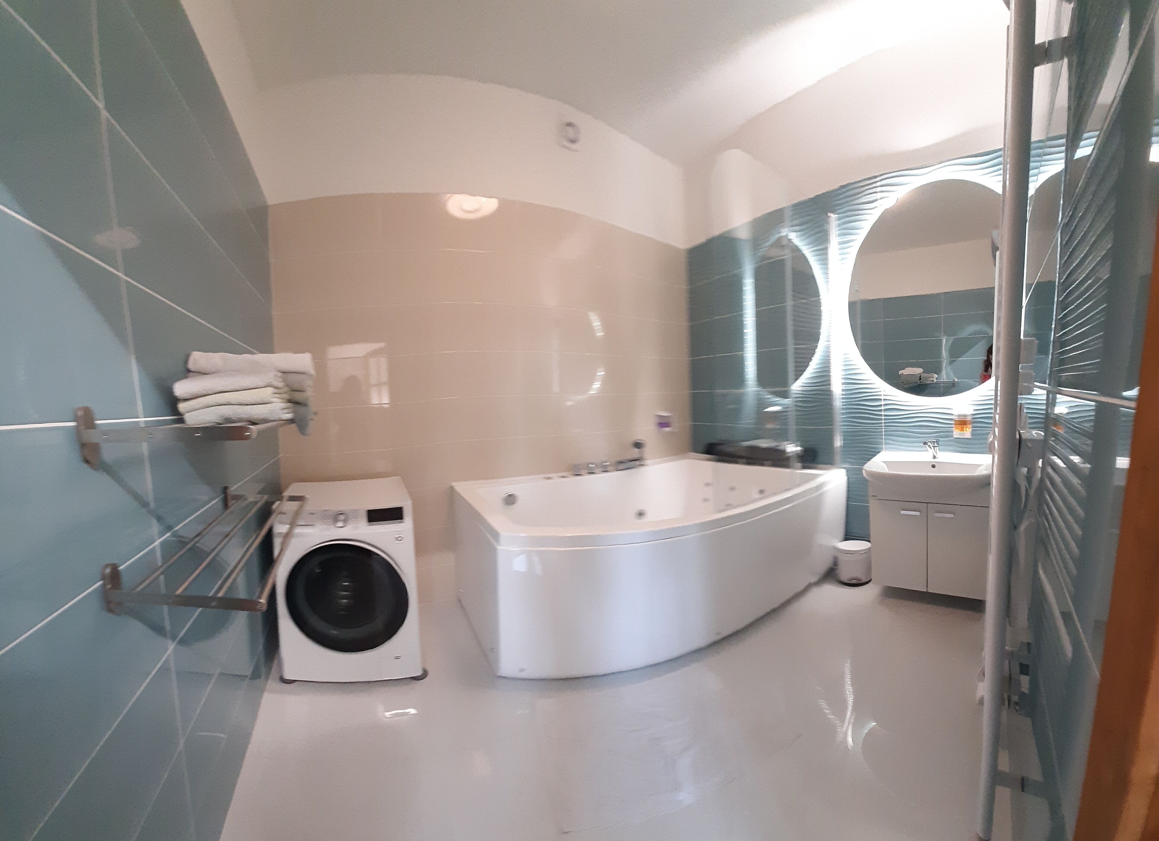 Ein modernes Badezimmer mit Waschmaschine, freistehender Badewanne und Waschtisch mit Spiegel.