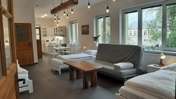 Une pièce chaleureuse et bien éclairée, avec un canapé, une table en bois et un coin cuisine.