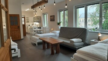 Una habitación acogedora y bien iluminada con sofá, una mesa de madera y una zona de cocina.