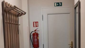 A hallway with a white door, a fire extinguisher, and a radiator.