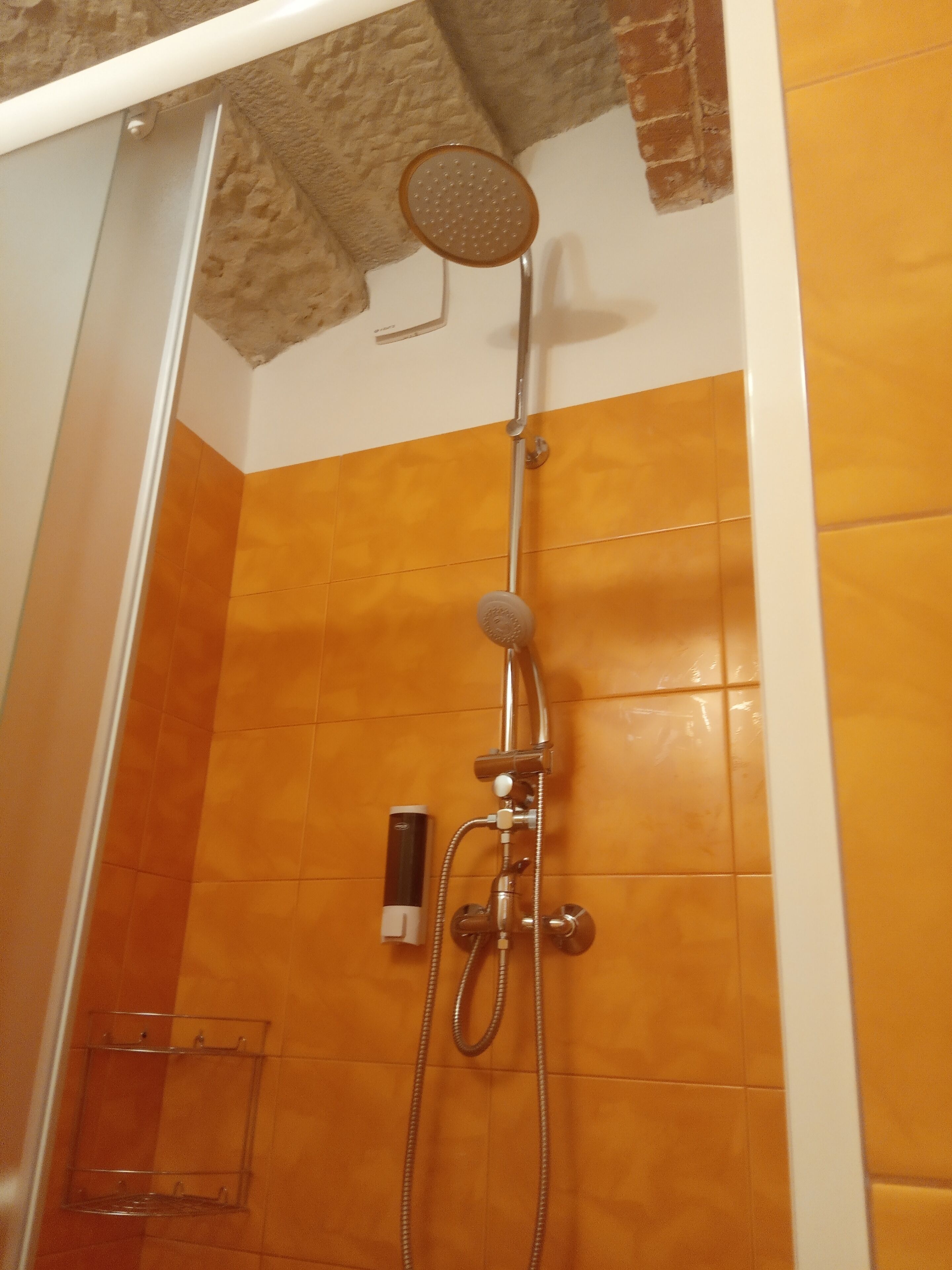 A shower with a handheld showerhead and a handheld shower attachment.