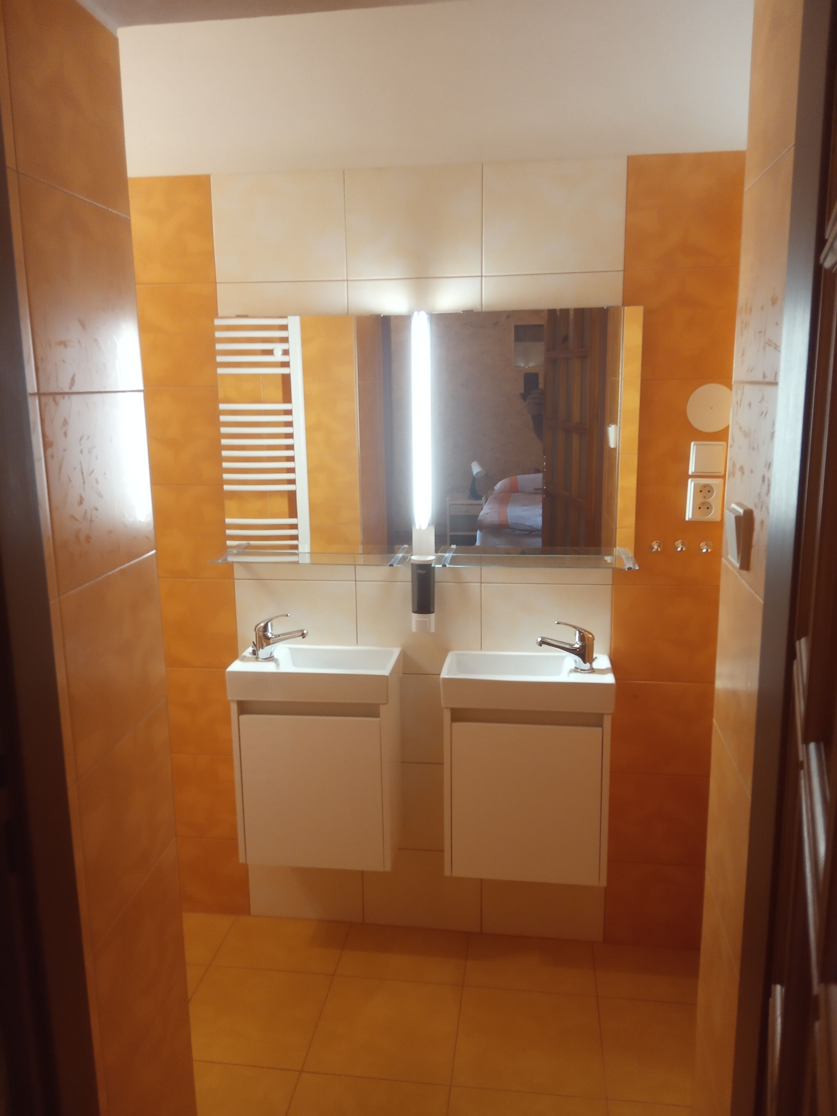 Un baño con dos lavamanos, un espejo y un perchero para toallas.