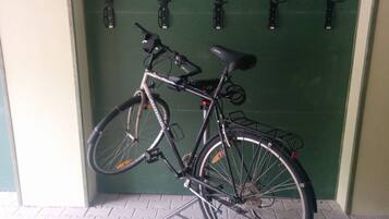 Un vélo est garé contre une porte verte, à côté d’un porte-vélo en métal.