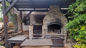Un four à pizza en pierre installé à l’extérieur, avec une table devant.