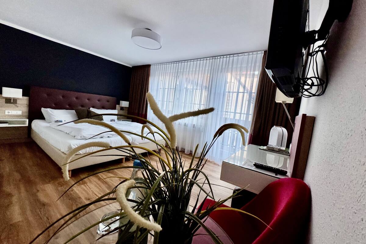 Habitación de hotel con cama, mesita de noche, l ámpara, televisor y escritorio con silla.
