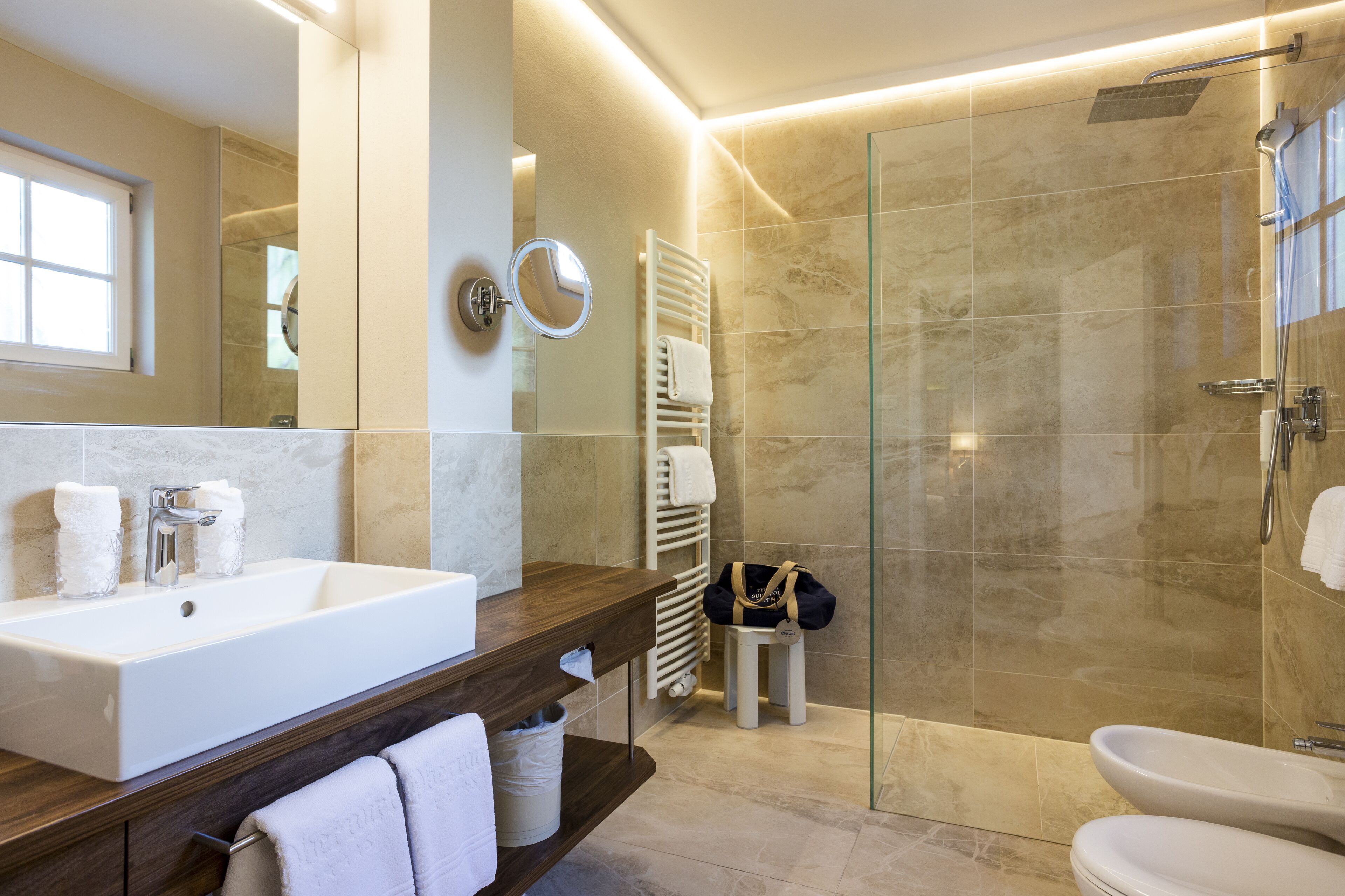 A modern bathroom with a large sink, mirror, and glass shower enclosure.