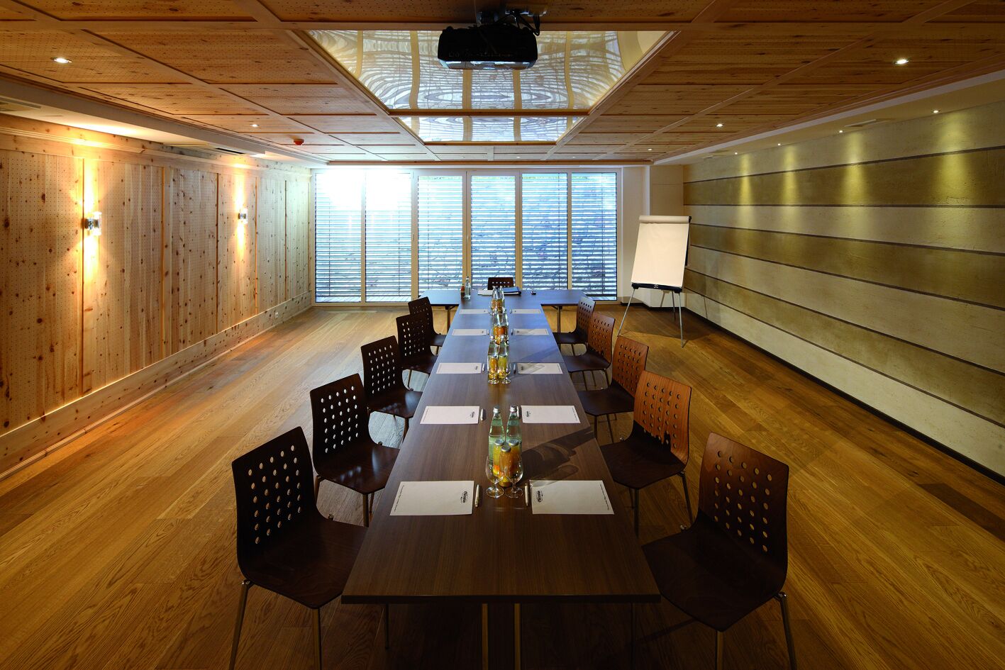 Une salle de conférence équipée d’une longue table, de chaises, d’un projecteur et d’un tableau blanc.