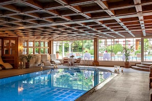 Una piscina cubierta, una piscina al aire libre, tumbonas