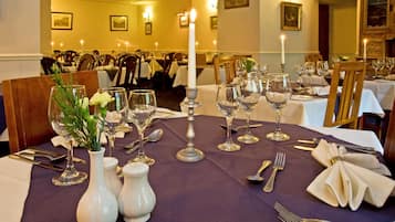 Una mesa de comedor dispuesta con mantel blanco, velas y cristalería.