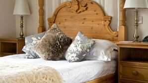 A neatly made bed with a fluffy white throw blanket, two wooden nightstands with lamps, and a wooden headboard with carved details. - New Dungeon Ghyll Hotel (Ambleside)