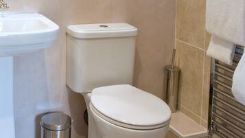 Un baño con inodoro blanco, lavamanos y cubo de basura.