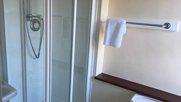 Un baño con cabina de ducha de vidrio, un perchero blanco y un inodoro blanco.