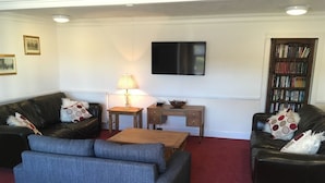 Een woonkamer met twee banken, een salontafel, een televisie en een boekenplank.