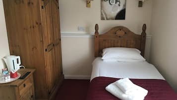 Un dormitorio con un armario de madera, una cama con ropa de cama blanca, un plaid rojo y dos lámparas de pared.