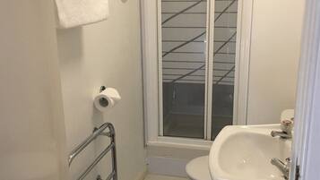Un baño pequeño con inodoro, lavamanos y ducha.