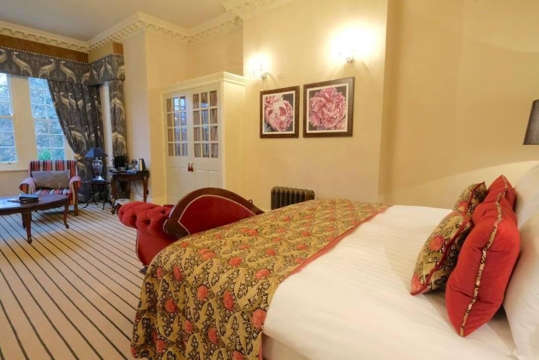 Een hotelkamer met een bed, een stoel, een tafel en een raam met gordijnen.
