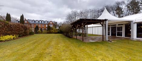 A grassy outdoor area with a covered pavilion and a white tent.