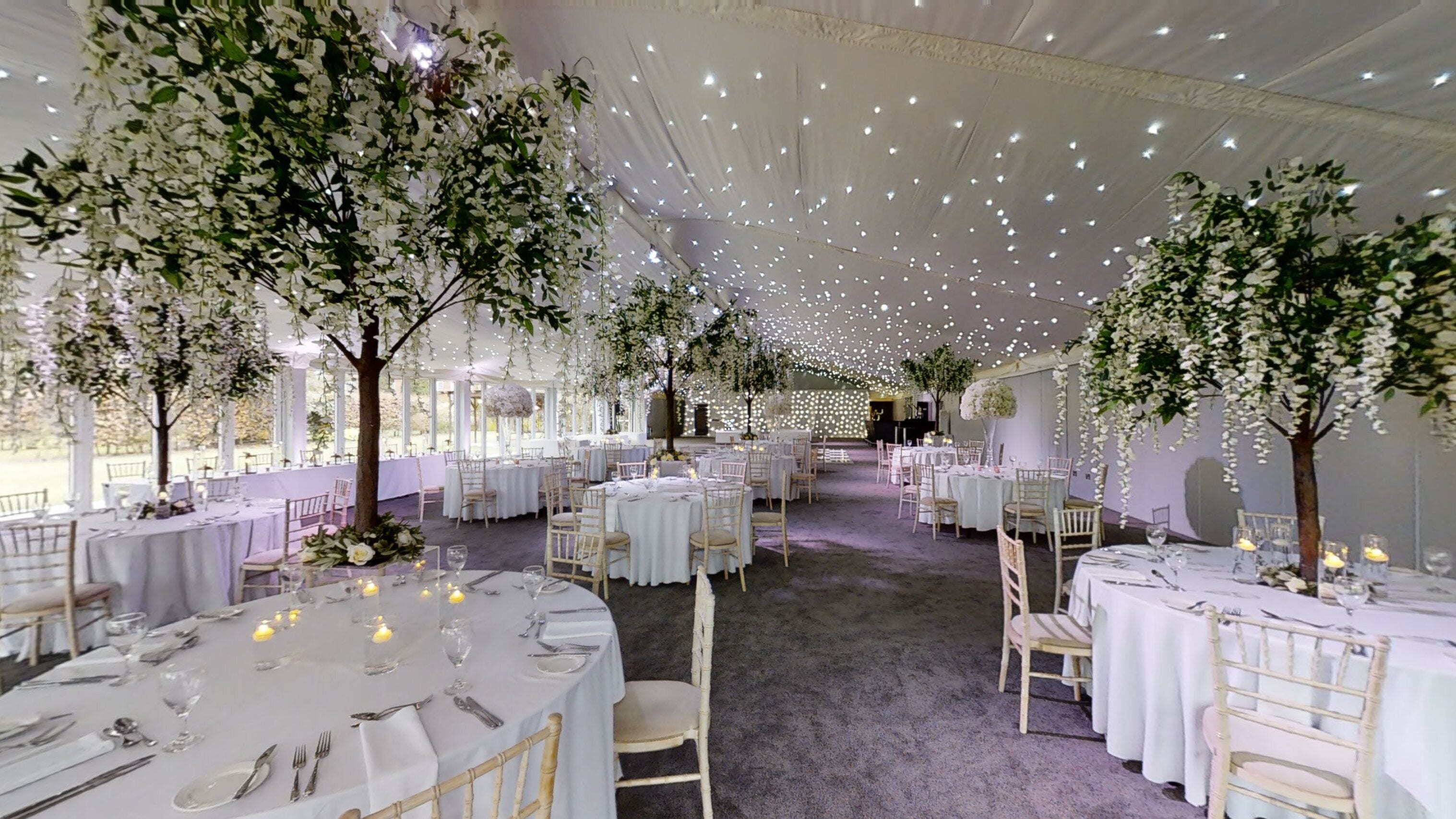 A banquet hall with round tables, white tablecloths, and chairs.