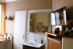 A bathroom with a white sink, a mirror, and a shelf with teddy bears.