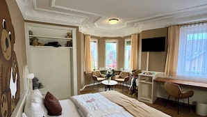 A hotel room with a large bed, a desk, a chair, and a television. - Teddybärenhotel (Kressbronn)