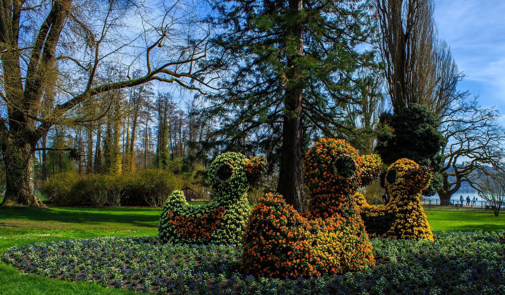 Un jardín con esculturas de animales hechas con setos, rodeado de abundante follaje y árboles.