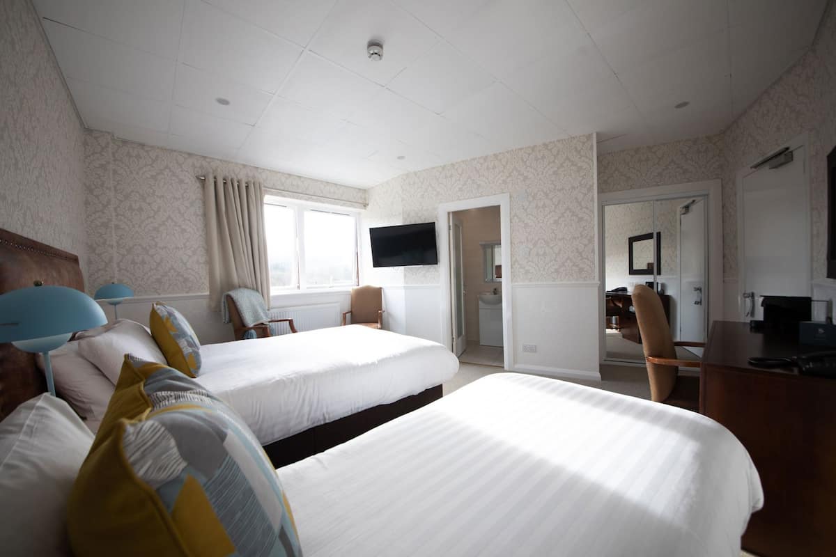 A hotel room with two beds, a TV, a desk, and a chair.