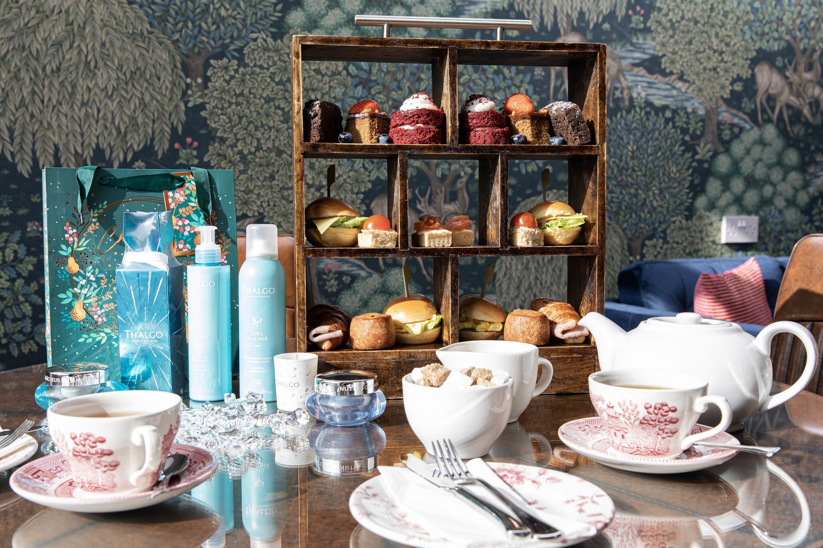 Une table dressée avec divers plats, une théière, des tasses et une boîte décorative.