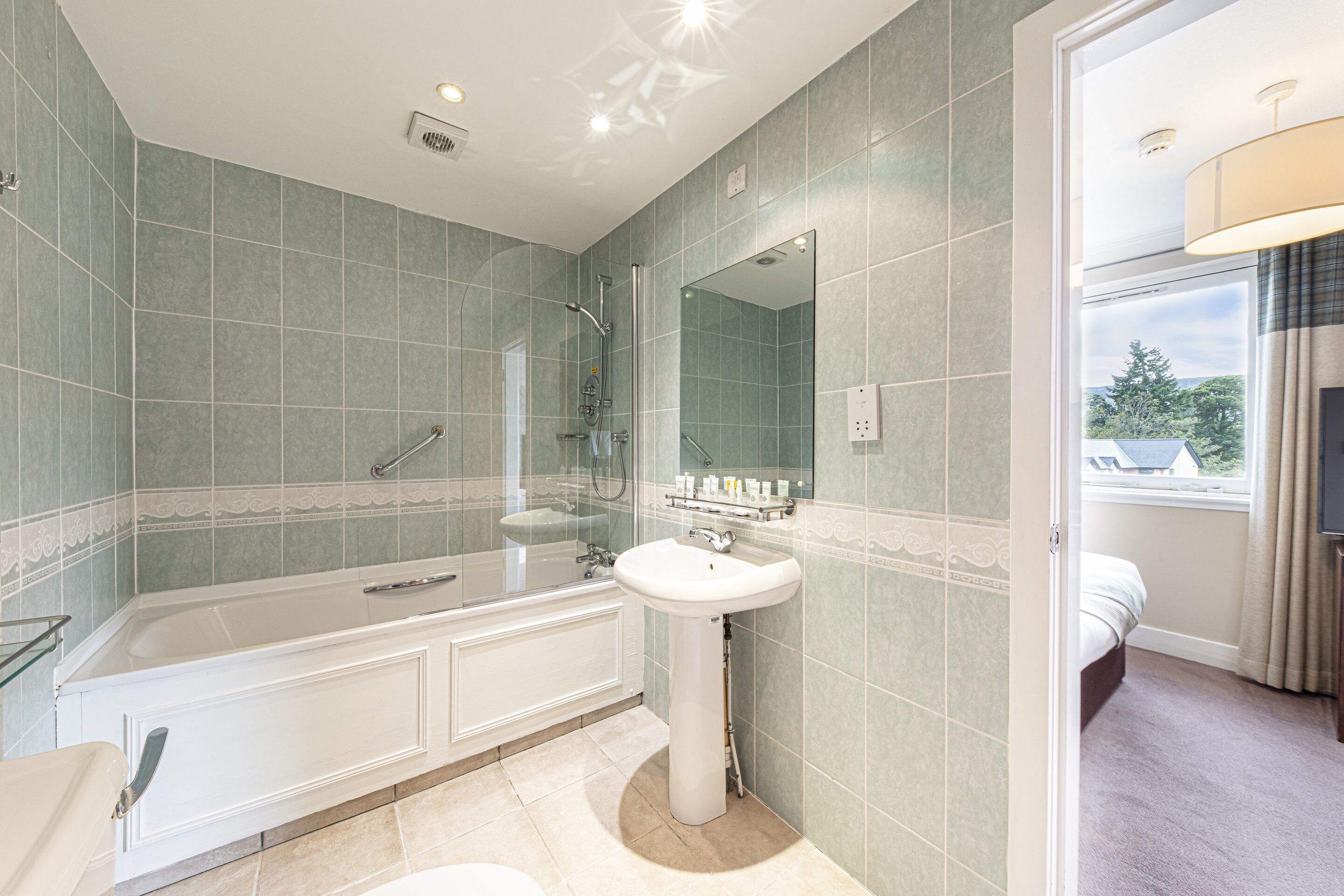 A modern bathroom with a large bathtub, a pedestal sink, and a shower.
