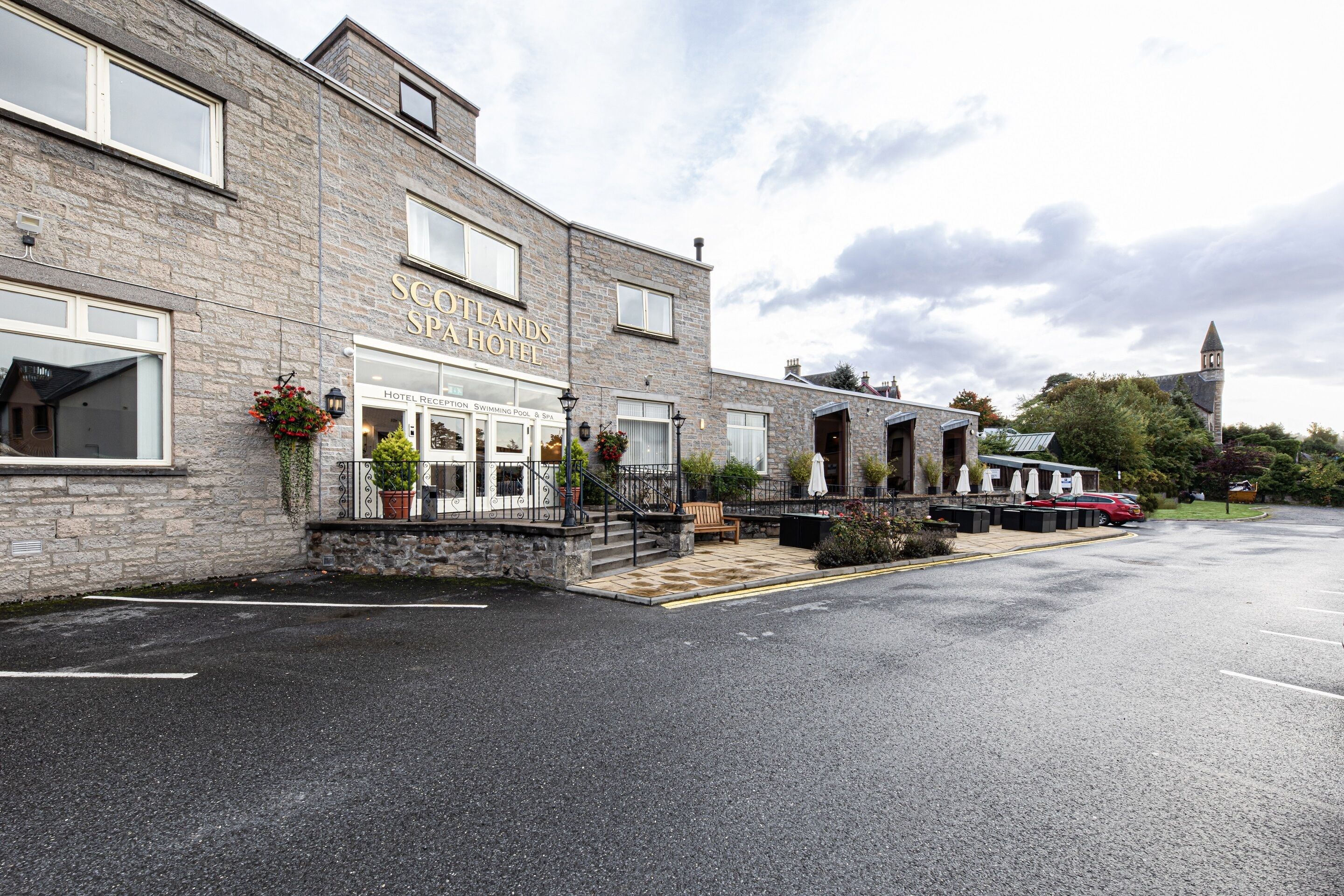 A hotel with a stone facade, a covered entrance, and a parking lot.
