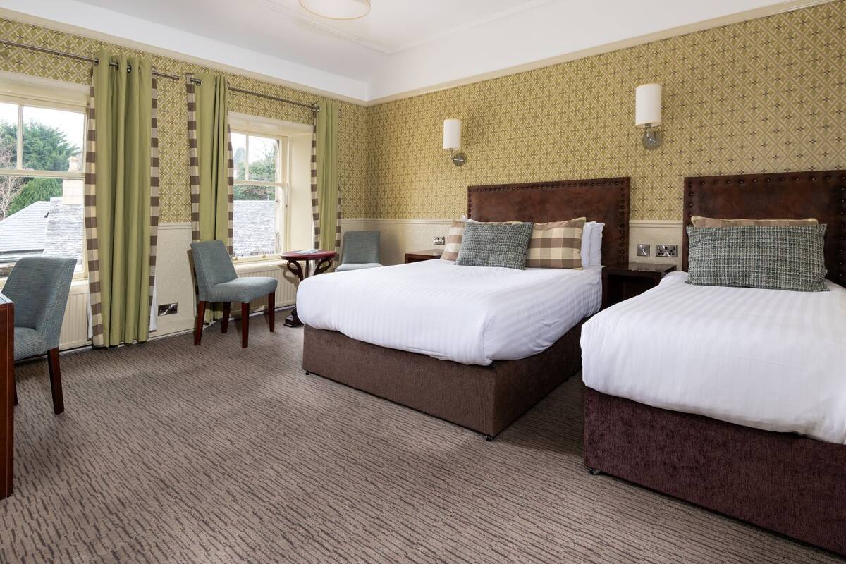 A hotel room with two beds, a desk, and a chair.