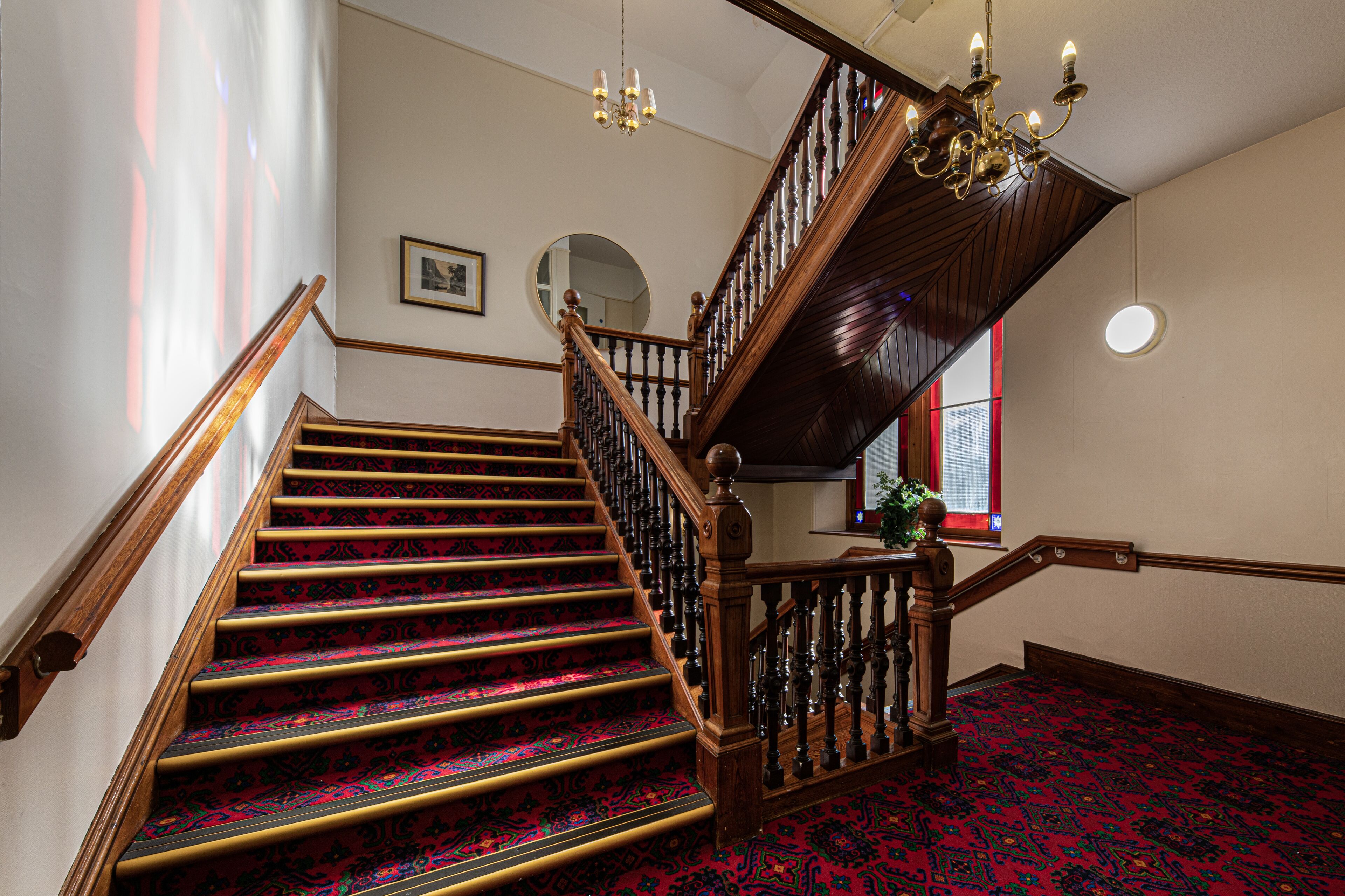 Una gran escalera con barandillas ornamentales y un suelo cubierto de alfombra roja.