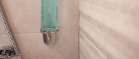 Baño con ducha, dispensador de jabón para manos y manguera de ducha.